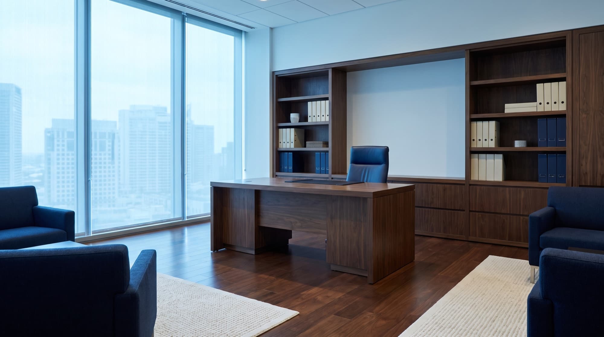 A private executive office with a walnut desk, navy leather chair, and a city view